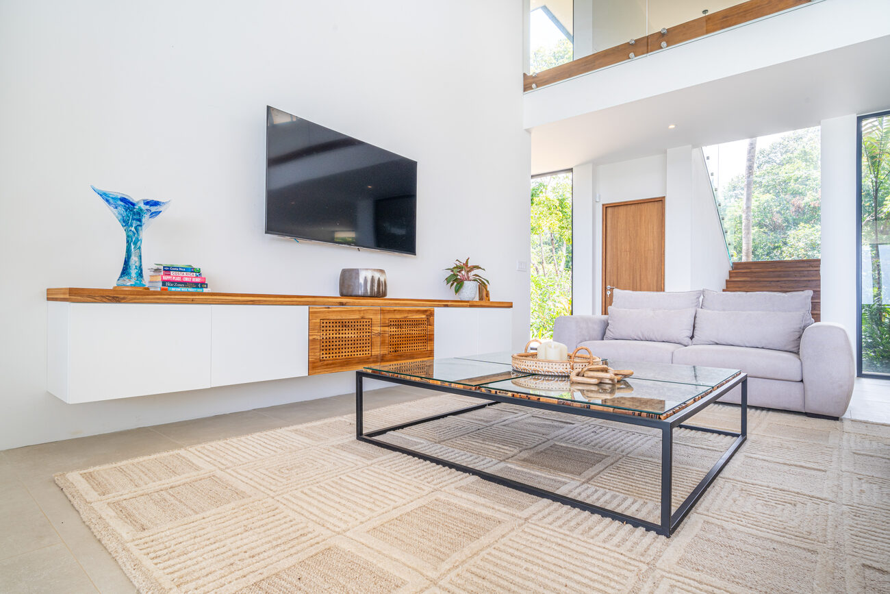 The double-height living room with floating media console and ocean-facing glass