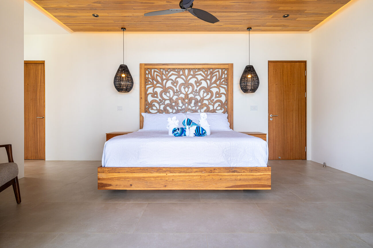 A king suite with a carved wood headboard, teak ceiling, and floating bed